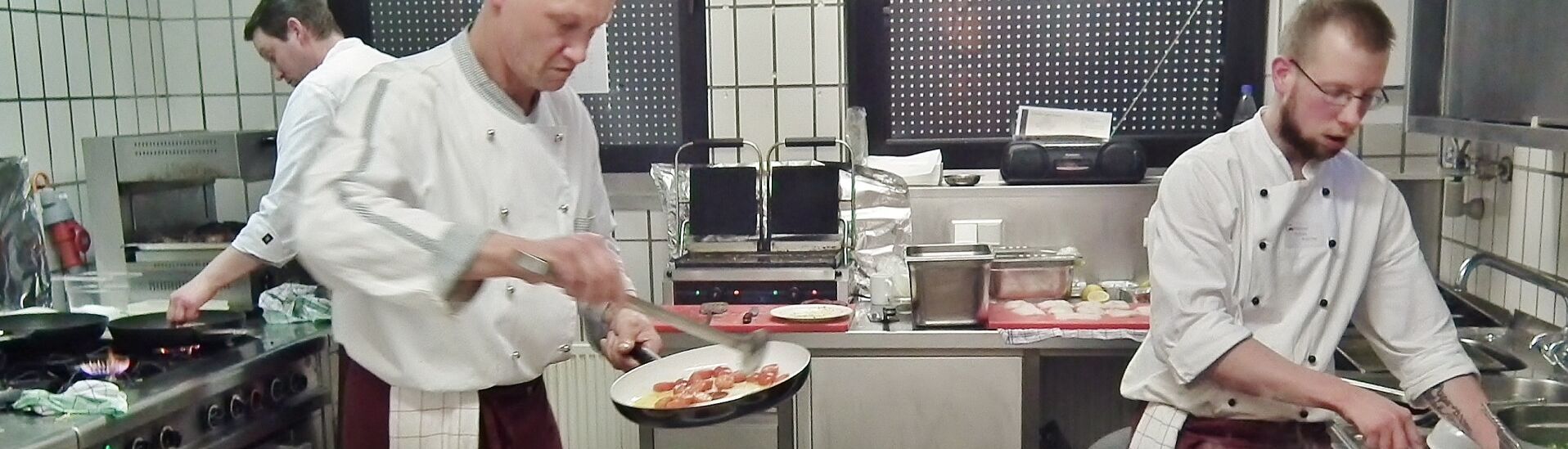 Zwei Köche beim Anrichte der Mittagsmahlzeit